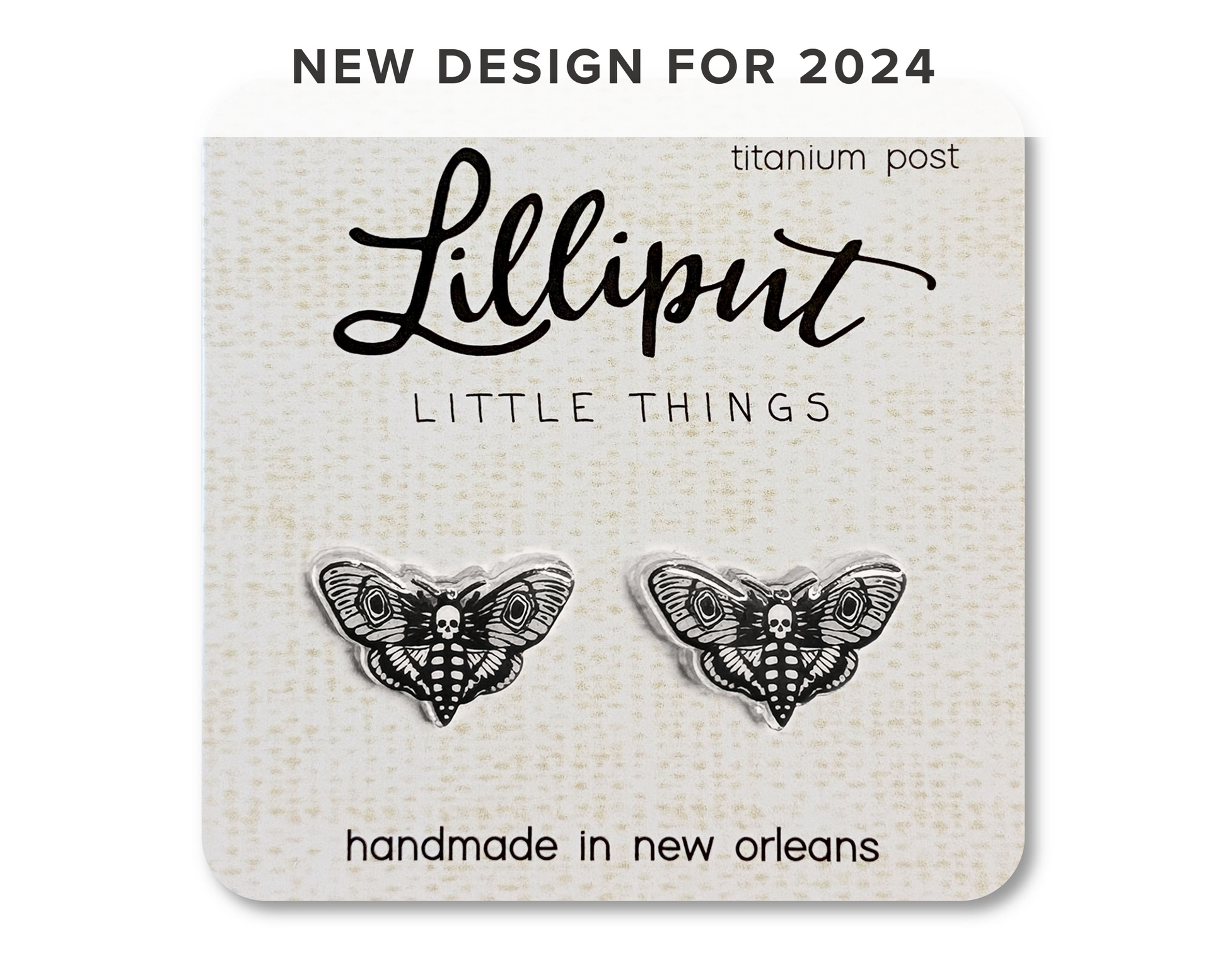 A pair of moth earrings with skull patterns on them, displayed on a card that reads 'Lilliput Little Things, handmade in New Orleans, Titanium Post"