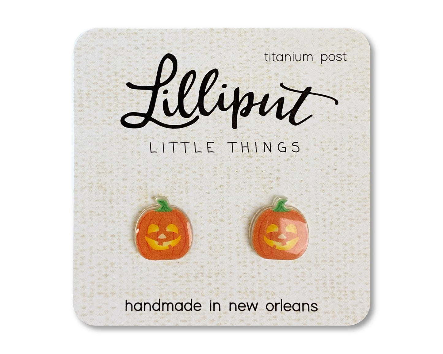 A pair of pumpkin shaped titanium earrings on a card that reads 'Lilliput Little Things, handmade in New Orleans, LA.'