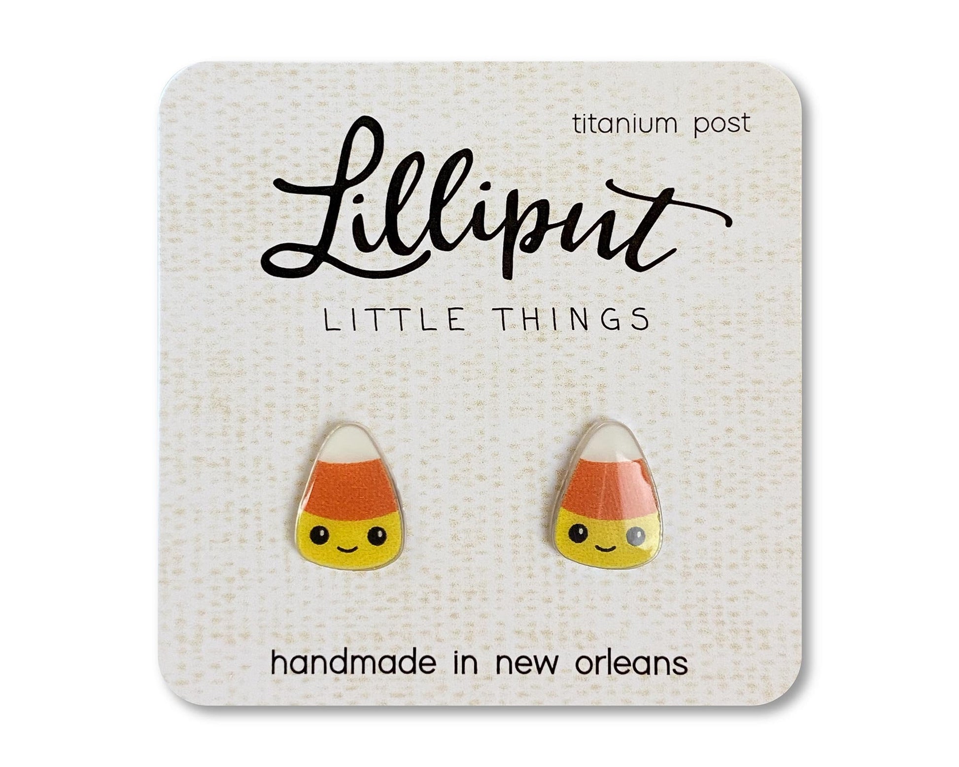 A pair of kawaii candy corn earrings on a card, with the brand name 'Lilliput Little Things' and 'handmade in New Orleans, titanium post' printed on it.